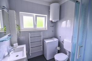 a white bathroom with a toilet and a sink at Apartments An Ni in Korčula