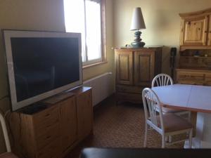 a living room with a television on a dresser with a table at Gîte Les Montagnes in Bolandoz