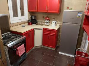 a kitchen with red cabinets and a stove and refrigerator at Maamoura Beach Zahraa Apartment 9/206 in Alexandria