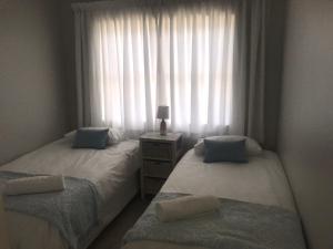 two twin beds in a bedroom with a window at Periwinkle Selfcatering 8 in Franskraal