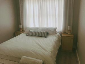a bedroom with a white bed with a window at Periwinkle Selfcatering 8 in Franskraal