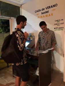 dos hombres parados junto a una mesa en una habitación en Pinamar Hostel Casa de Verano, en Pinamar