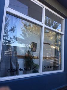 una ventana con un reflejo de una persona en ella en Pinamar Hostel Casa de Verano en Pinamar