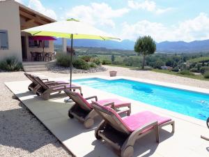 a pool with chairs and an umbrella next to a house at LES HAUTS DE JALLIA in Sainte-Jalle