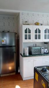 una cocina con nevera de acero inoxidable y armarios blancos en Casa en algarrobo, en Algarrobo