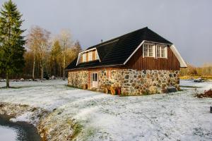 una casa de piedra en la nieve junto a un río en Loovälja Guesthouse en Limu
