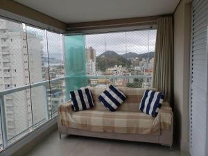 uma sala de estar com um sofá em frente a uma grande janela em Apto com Vista para o Mar e ampla Varanda Gourmet no Guarujá