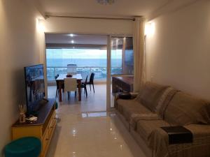uma sala de estar com um sofá, uma televisão e uma mesa em Apto com Vista para o Mar e ampla Varanda Gourmet no Guarujá