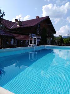 a swimming pool with a chair in front of a house at Sadyba Iryna Садиба Ірина in Tukhlya