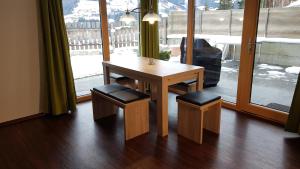 a wooden table and two stools in a room with a window at Haus Sabrina in Kaltenbach