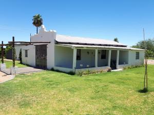 a white house with a palm tree in the yard at Avonsrus Guesthouse in Augrabies