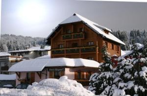 a large wooden building covered in snow at Chalet Hotel Régina in Les Gets