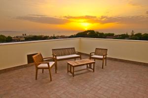 a balcony with chairs and a table and a sunset at Erice Mare in Erice