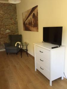 a living room with a television on a white dresser at Suite CALLIOPE - LE MUSE in Pietrasanta