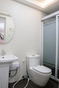 a white bathroom with a toilet and a sink at Mezza Hotel in Koronadal