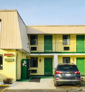 a car parked in front of a building with green doors at Granada Inn Motel - Kalkaska in Kalkaska