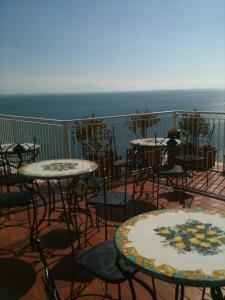 a balcony with tables and chairs and the ocean at Hotel Voce del Mare in Vietri sul Mare