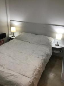 um quarto com uma cama branca e 2 candeeiros em Departamento Leben em Colón