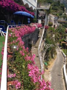 a group of stairs with pink flowers and an umbrella at Hotel Voce del Mare in Vietri sul Mare