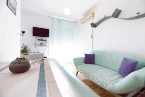 uma sala de estar com um sofá azul e almofadas roxas em Apartment DORA Split em Split