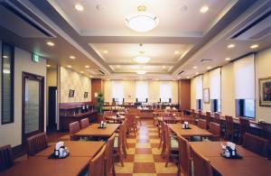 a restaurant with wooden tables and chairs at Hotel Route-Inn Shibata Inter in Shibata