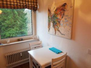 einen Tisch und Stühle in einem Zimmer mit Schmetterlingsgemälde in der Unterkunft Fewo Aurora in Hahnenklee-Bockswiese