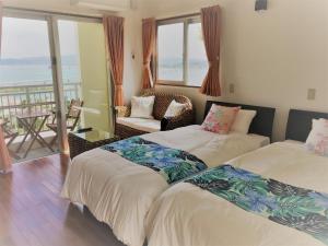 two beds in a room with a view of the ocean at シーブリーズ古宇利 in Nakijin