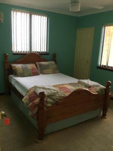 a bed in a bedroom with green walls and windows at Shark Bay Views B & B in Denham