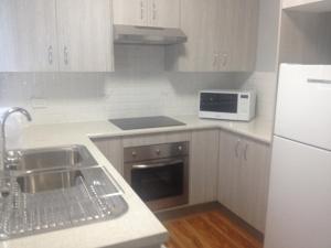 a white kitchen with a sink and a microwave at Mystic Blue and Green Meadow in Nowra