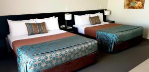 una habitación de hotel con 2 camas y una falda en Royal Motel Miles, en Miles