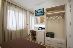 Schlafzimmer mit einem Bett, einem Schreibtisch und einem TV in der Unterkunft La Casa del Turista in Gallipoli