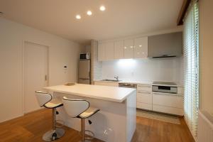 a kitchen with a white counter and two stools at North Star Hirafu in Niseko