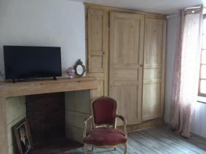 a room with a fireplace with a tv and a chair at Chez Mémère Hélène in Sormonne
