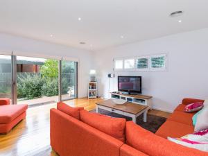 a living room with two orange couches and a television at Torquay Timeout in Torquay