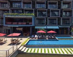 a hotel with a swimming pool with tables and umbrellas at Inthira Vangvieng in Vang Vieng