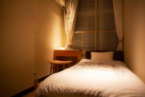 - une petite chambre avec un lit et une table dans l'établissement Aizu Higashiyama Onsen Tsuki no Akari, à Aizuwakamatsu