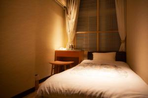 a small bedroom with a bed and a table at Aizu Higashiyama Onsen Tsuki no Akari in Aizuwakamatsu