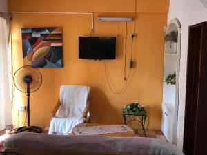 Zimmer mit einem Stuhl und einem TV an der Wand in der Unterkunft Sun Tropical Paradise in Belle Mare