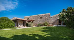 a large stone house with a grass yard at Il Rudere in Gonnesa