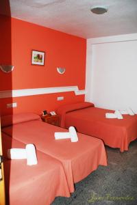 2 camas en una habitación con paredes rojas en Hostal Mary Tere en Salobreña