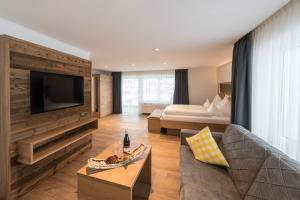 a large living room with a couch and a tv at Hotel Alpenblick in Fischen