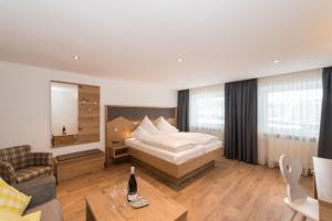 Habitación de hotel con cama y sofá en Hotel Alpenblick en Fischen