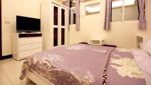 Schlafzimmer mit einem Bett und einem Flachbild-TV in der Unterkunft Summer House in Altstadt von Hengchun