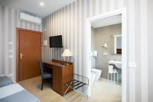 a hotel room with a desk and a bathroom at Hotel Excelsior Pavia in Pavia