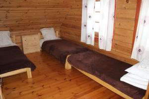 Habitación con 3 camas en una cabaña de madera en Aido ir Vido sodyba en Utena