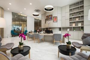 a lobby with chairs and tables with flowers on them at Pinetree Marina Resort in Nusajaya