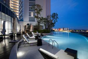 a large swimming pool in a building with chairs at Pinetree Marina Resort in Nusajaya