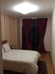 a bedroom with a white bed and red curtains at ADALBERTO NASCIMENTO LUXURY APARTA-HOSTEL At COLINAS DO CRUZEIRO in Odivelas