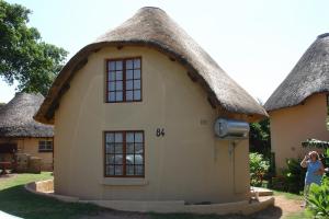 a woman standing in front of a house with a thatched roof at Hibberdene Hideout in Hibberdene