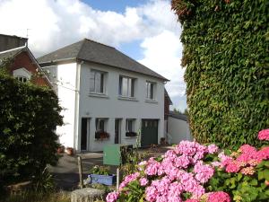 una casa blanca con flores rosas delante en Gite Hénanbihen, en Hénanbihen